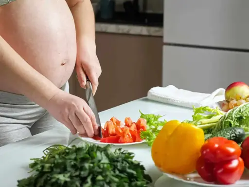 Schwangere bereitet gesunde Mahlzeit zu. Bunte Paprika, Tomaten und frisches Gemüse für eine gute Ernährung während der Schwangerschaft.