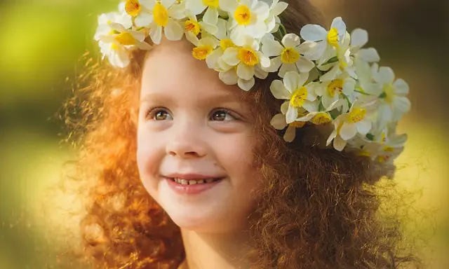 Ein Mädchen mit roten Locken und einem Blumenkranz im Haar, das an keltische Namen weiblich erinnert.