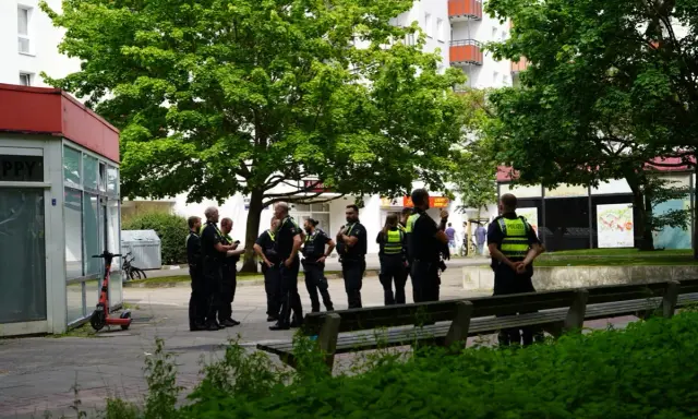 Polizei schreitet ein, wo ein familienstreit eskaliert was tun? Mehrere Beamte stehen vor einem Geschäft und beraten sich.