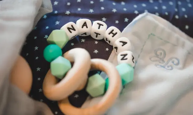Ein Beißring mit den Buchstaben "NATHAN" und mintgrünen Perlen. Perfekt für super coole Jungennamen!