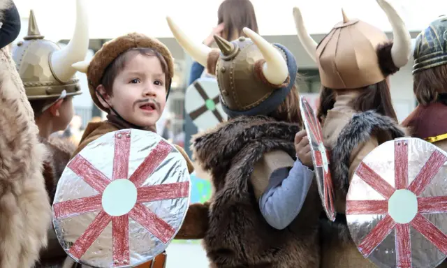 Kinder in Wikingerkostümen mit Hörnerhelmen und Schilden. Vielleicht sind das zukünftige Krieger mit Namen wie Ragnar oder Björn, die sich auf ihre Wikinger-Jungennamen vorbereiten.
