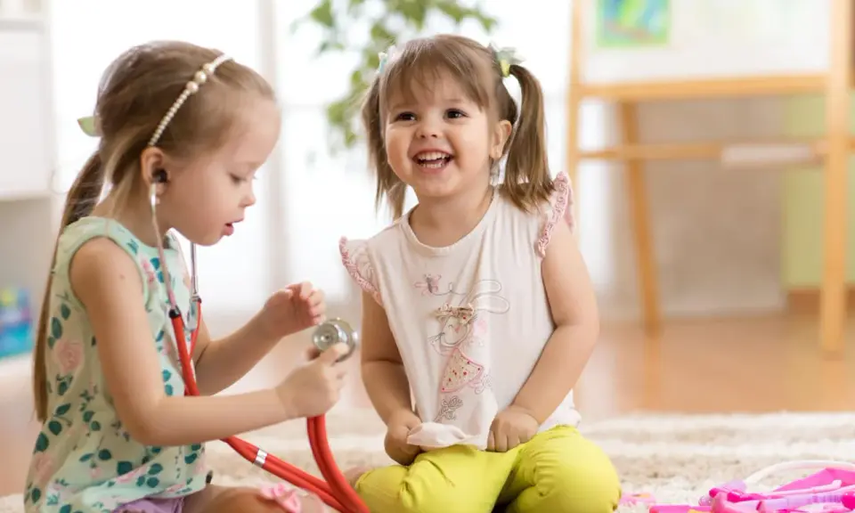 Zwei Mädchen spielen Arzt. Das eine Kind, etwa 7 Jahre alt, untersucht das andere mit einem Stethoskop. Ein spielerischer Einblick in die sexuelle Entwicklung eines Kindes.