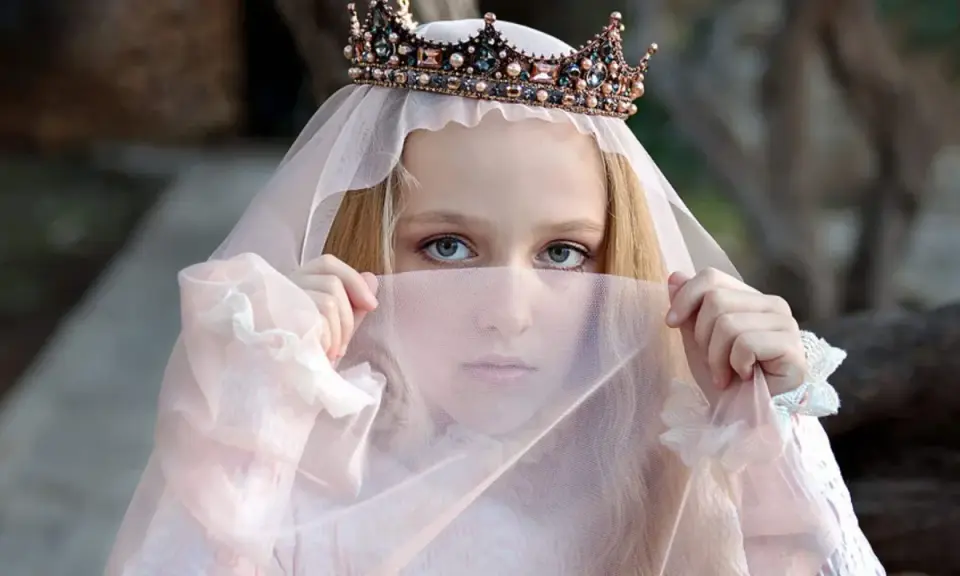 Ein Mädchen mit Krone und Schleier, wie eine Prinzessin aus Herr der Ringe Namen weiblich, blickt geheimnisvoll hervor.
