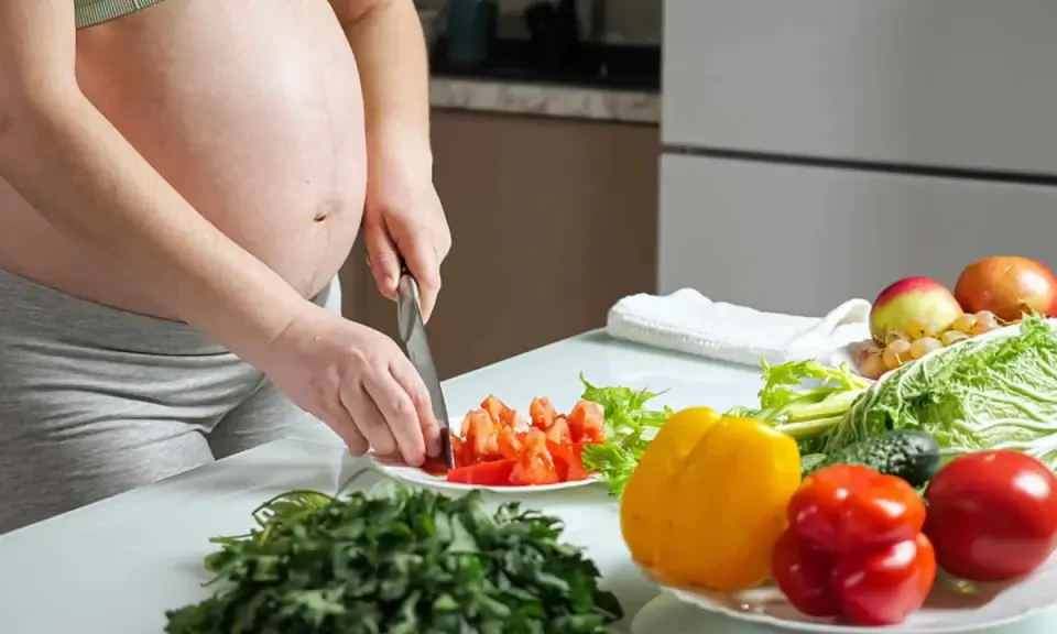 Schwangere bereitet gesunde Mahlzeit zu. Bunte Paprika, Tomaten und frisches Gemüse für eine gute Ernährung während der Schwangerschaft.