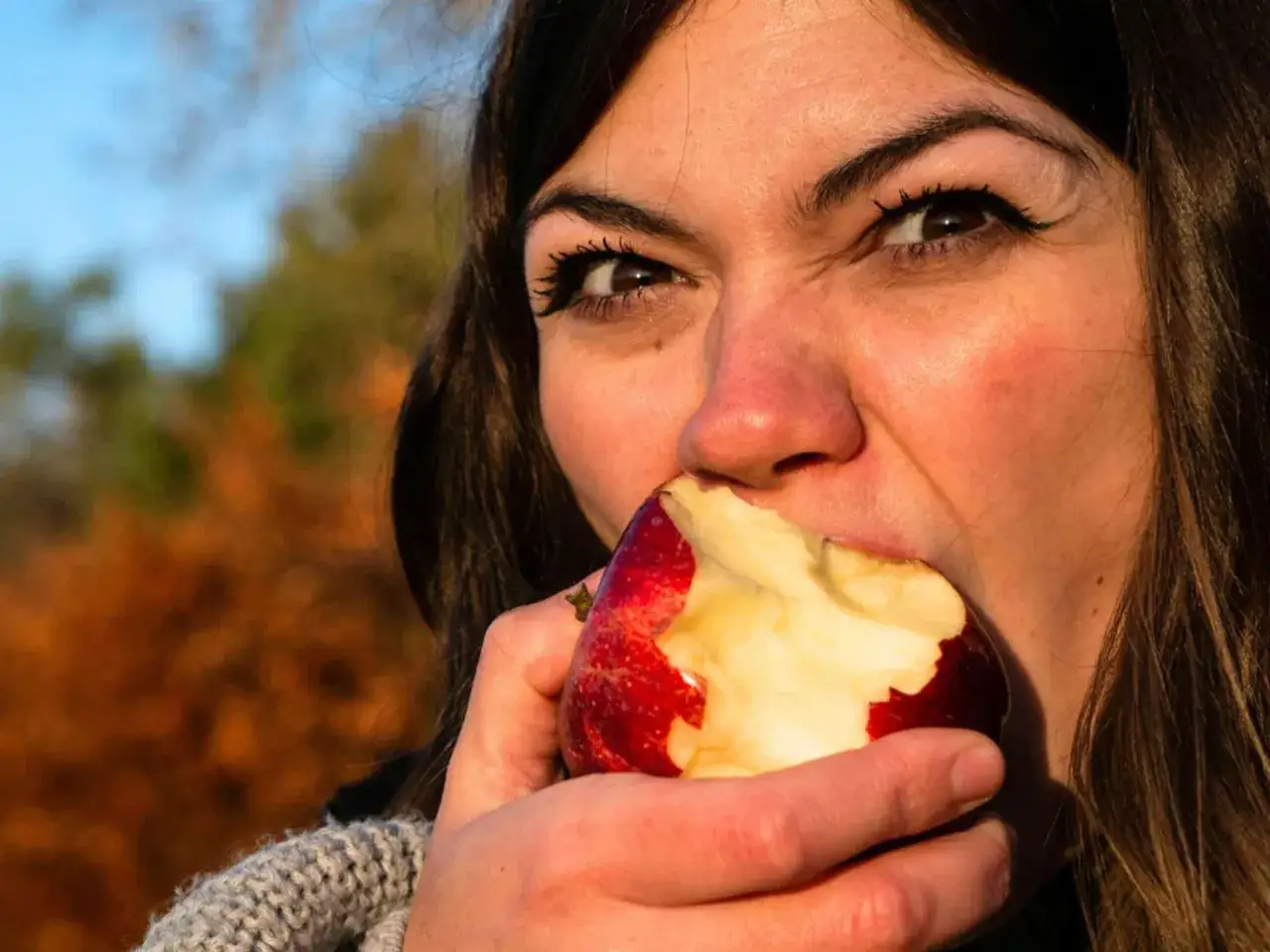 Frau beißt in einen roten Apfel. Vielleicht ein gesunder Snack während der Schwangerschaft.