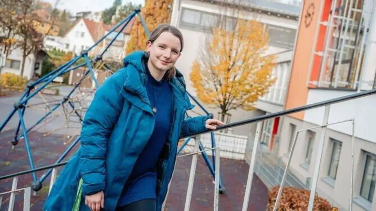 Junge Frau auf einem Schulhof, die sich fragt, warum ein Kind nicht mitspielen darf. Grundschule im Herbst.