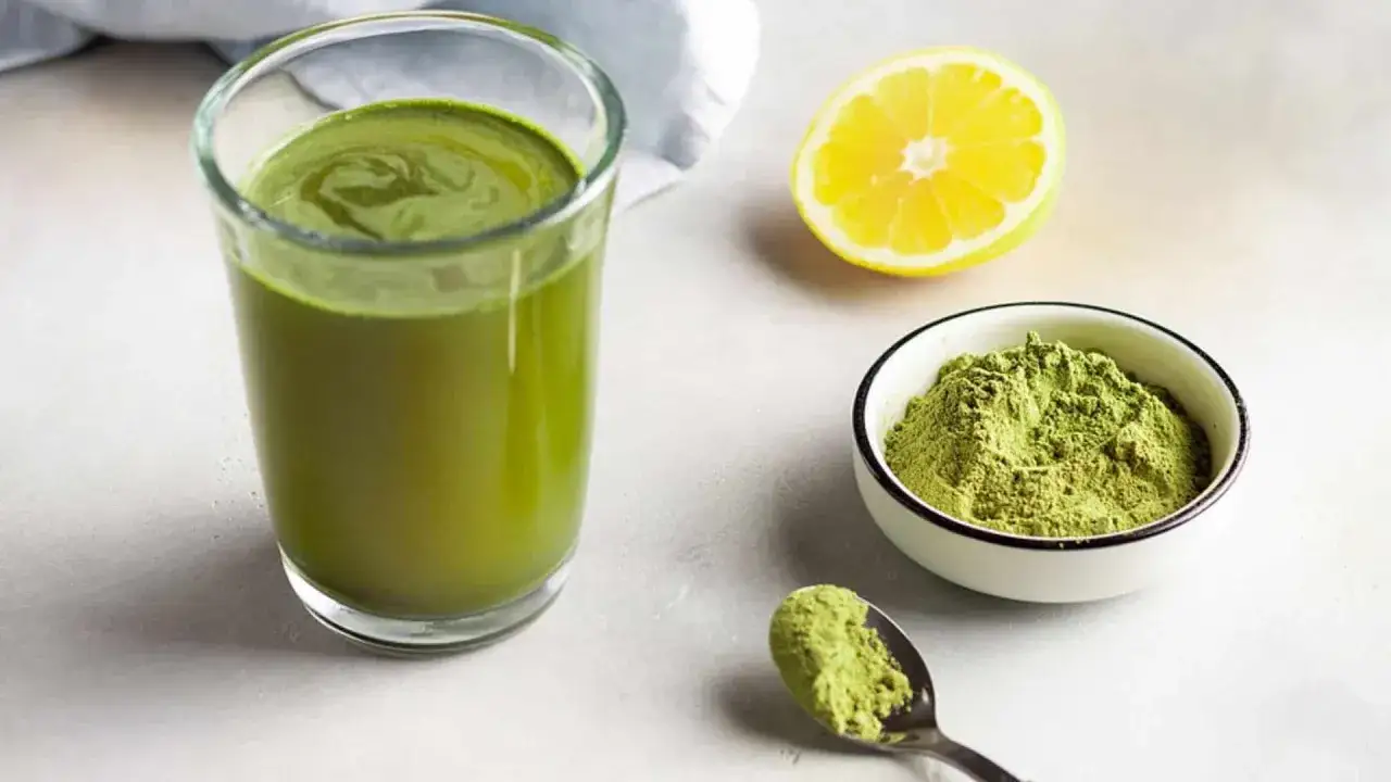 Ein Glas grüner Gerstengras-Smoothie, eine Schale mit Gerstengraspulver und eine Zitronenhälfte. Ideal für die Stillzeit.