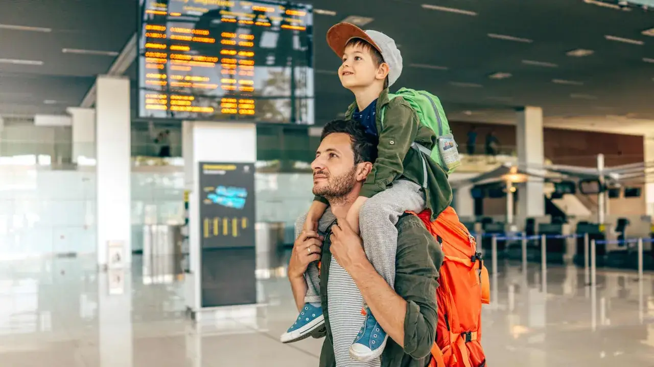 Vater tr&auml;gt Sohn auf den Schultern am Flughafen. Ein Abenteuer beginnt, alleine reisen mit Kind.