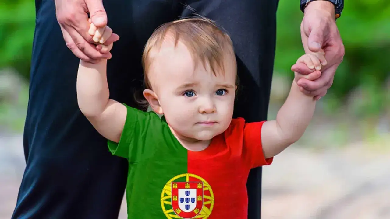 Ein s&uuml;&szlig;es Baby mit portugiesischer Flagge auf dem T-Shirt, gehalten von einer Hand. Vielleicht ein zuk&uuml;nftiger Jo&atilde;o oder Miguel, inspiriert von portugiesischen Jungennamen.