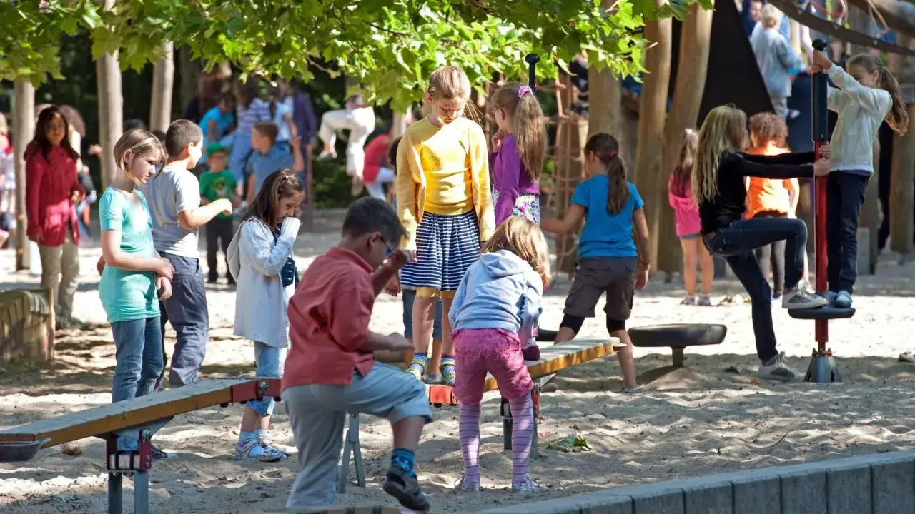 Kinder spielen und lachen auf einem Spielplatz. Sie sind Freunde, die gemeinsam Spa&szlig; haben und die Sonne genie&szlig;en.