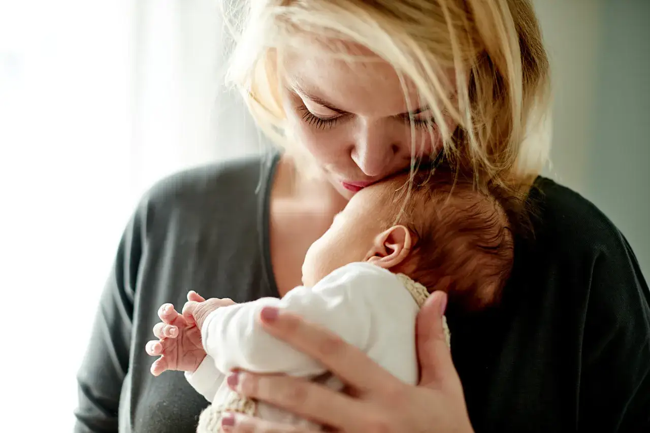 Eine Mutter k&uuml;sst ihr Baby. Die zarte mama phase, voller Liebe und Geborgenheit, wird hier eingefangen.