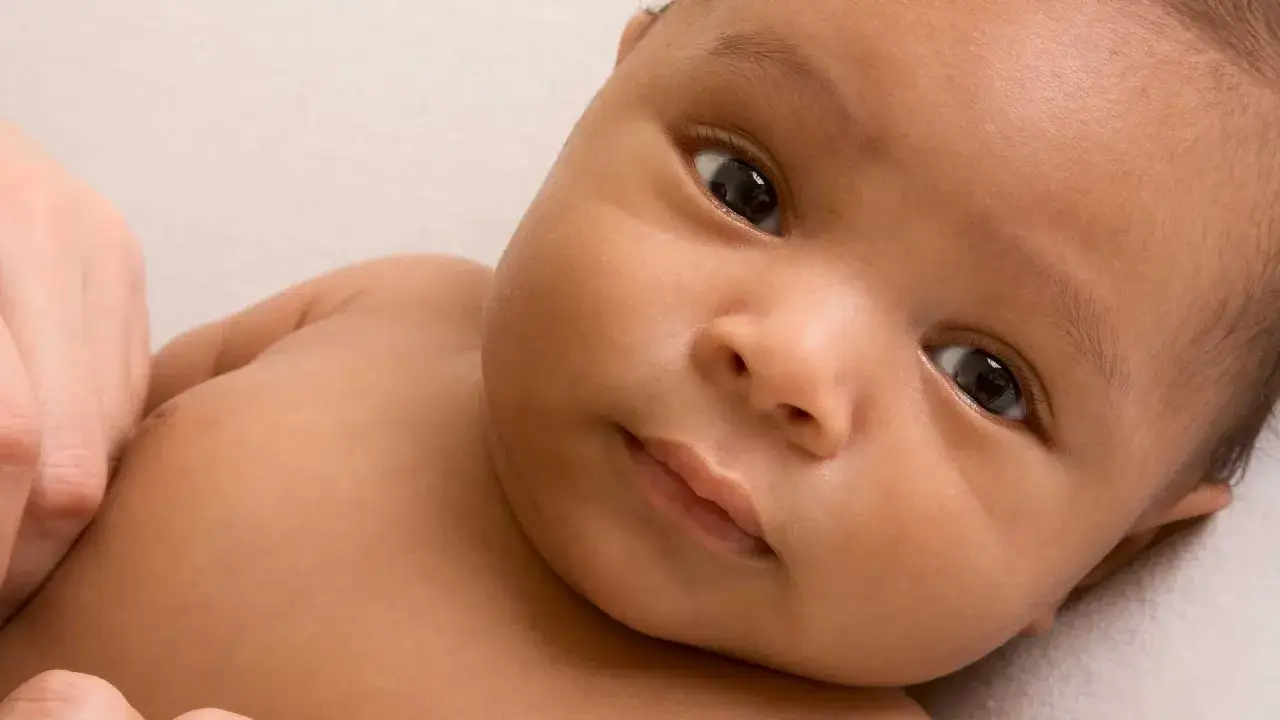 Ein neugeborenes Baby mit dunkler Haut und gro&szlig;en, dunklen Augen. Vielleicht ein Name wie Omar oder Layla, typisch f&uuml;r syrische Namen.