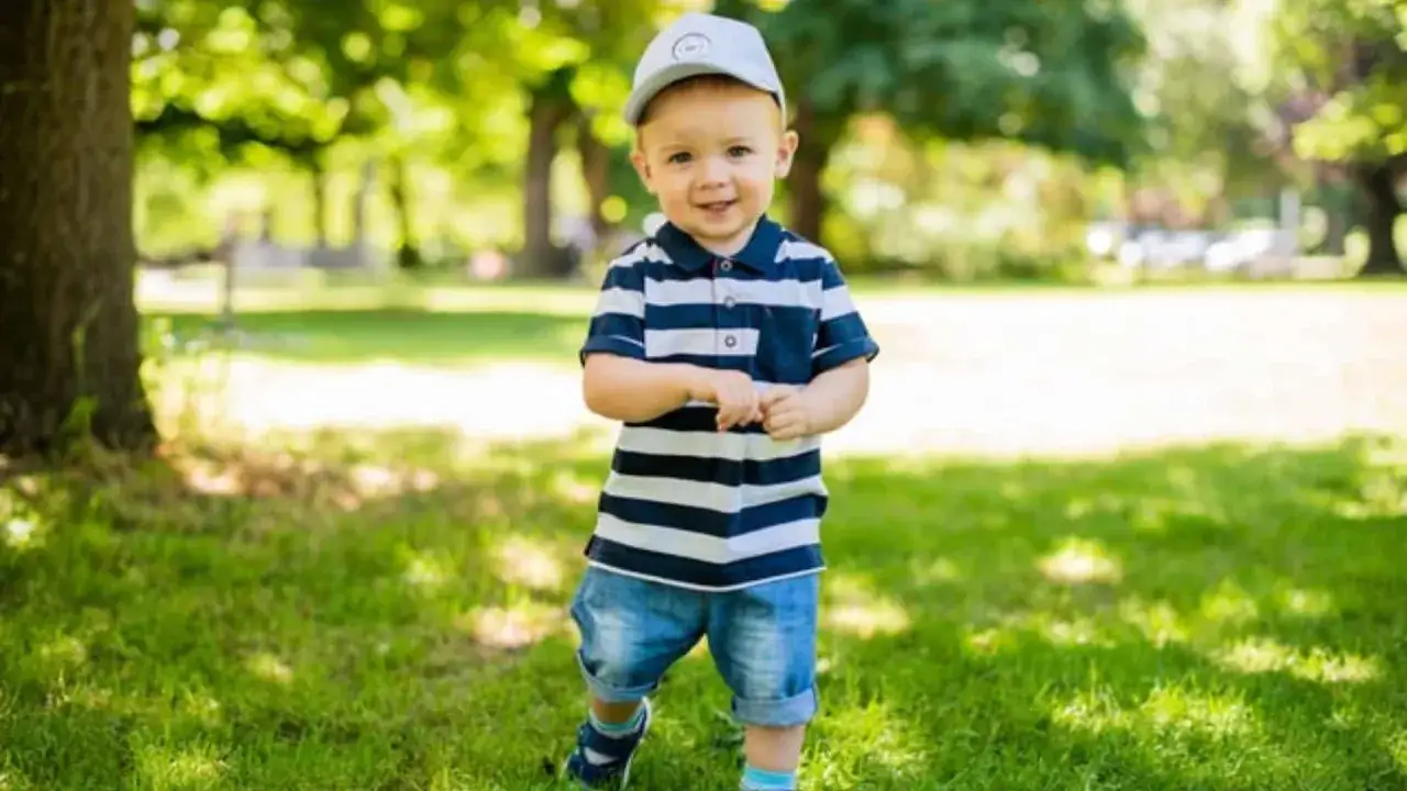 Ein fr&ouml;hlicher Junge mit einem gestreiften Polo und Jeans steht im Park. Vielleicht hei&szlig;t er Finn, Leo oder Noah &ndash; beliebte Jungennamen mit 4 Buchstaben.