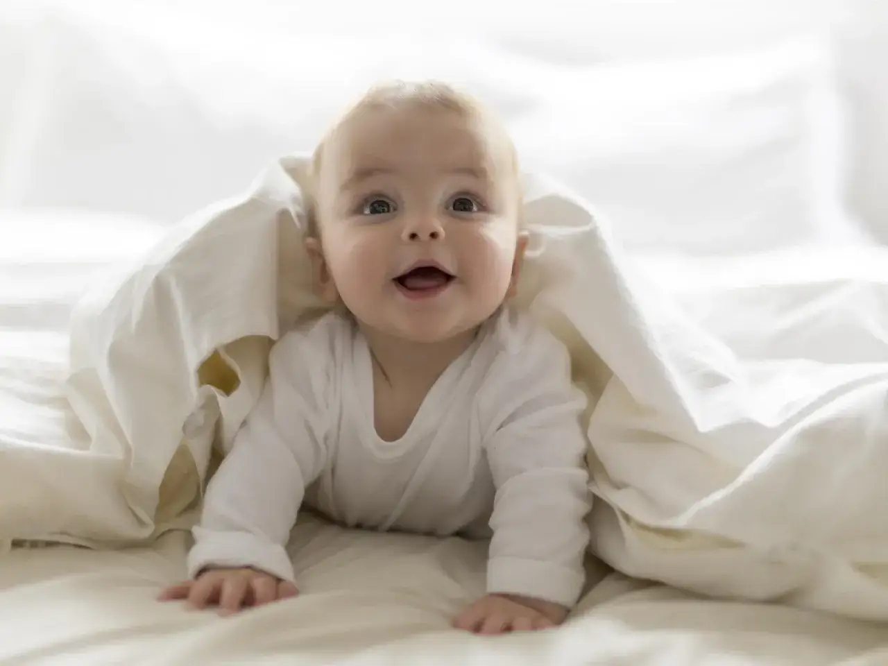 Ein l&auml;chelndes Baby versteckt sich unter einer Decke. Vielleicht ein zuk&uuml;nftiger Noah oder ein kleiner David, inspiriert von Jungennamen Bibel.