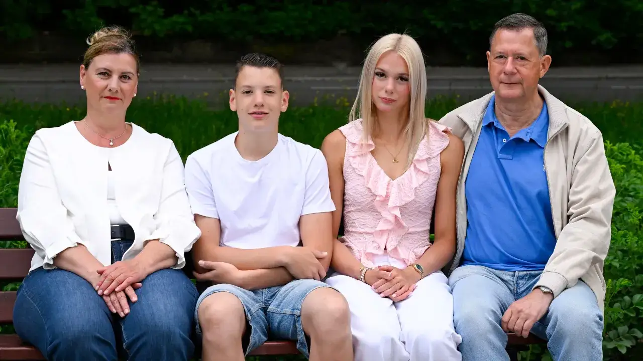 Familie sitzt auf einer Bank. Die Frau denkt &uuml;ber den mental load nach, w&auml;hrend die Kinder und der Mann entspannt wirken.