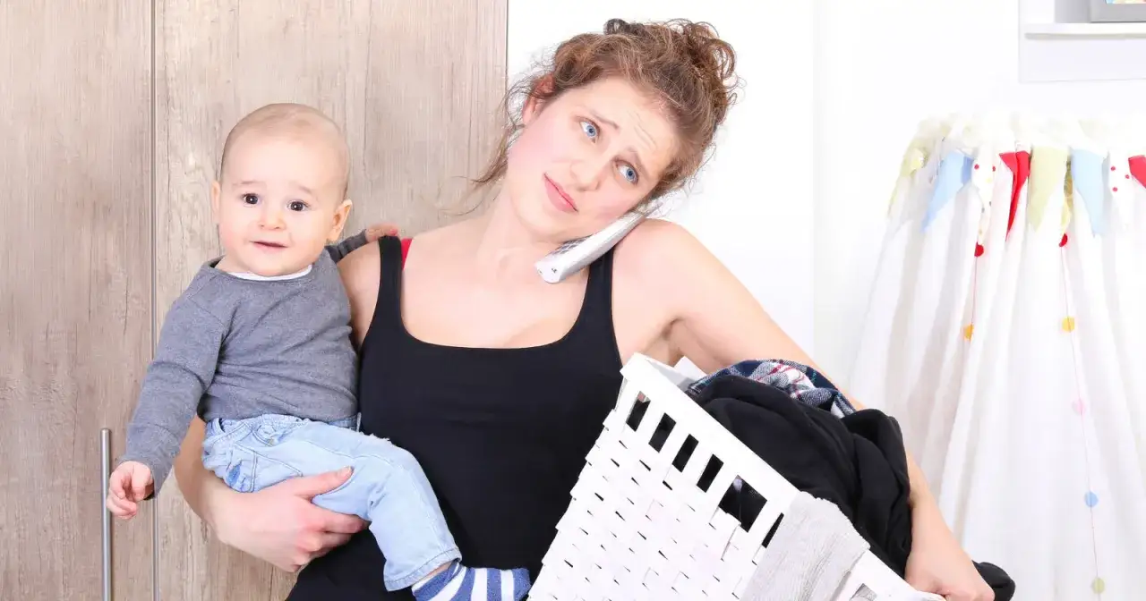 &Uuml;berforderte Mutter mit Baby am Telefon, W&auml;schekorb in der Hand. Symptome von 