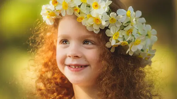 Ein Mädchen mit roten Locken und einem Blumenkranz im Haar, das an keltische Namen weiblich erinnert.