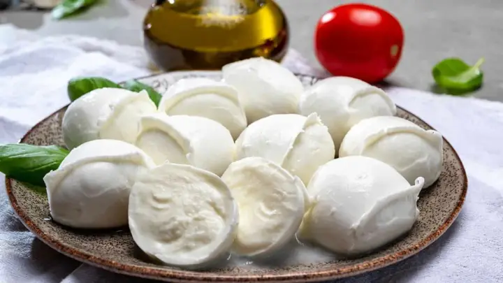 Frische Mozzarellakugeln auf einem Teller, garniert mit Basilikum. Perfekt für eine leichte Mahlzeit während der Schwangerschaft.
