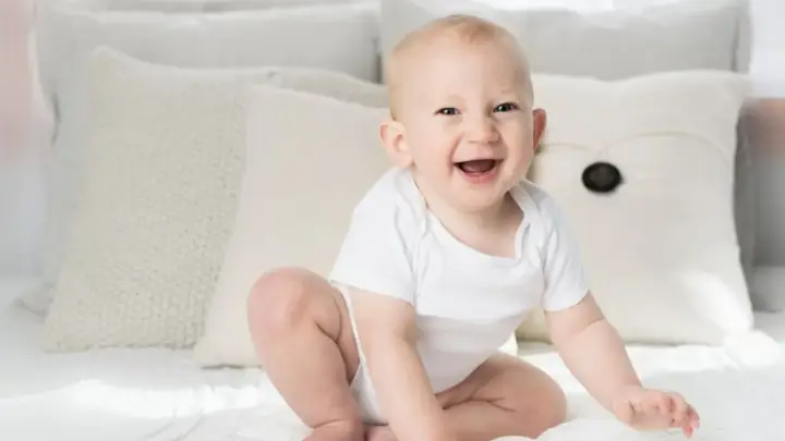Ein strahlendes Baby, ein echtes Kind der Sonne, sitzt auf einem Bett. Elias' Lachen ist ansteckend.