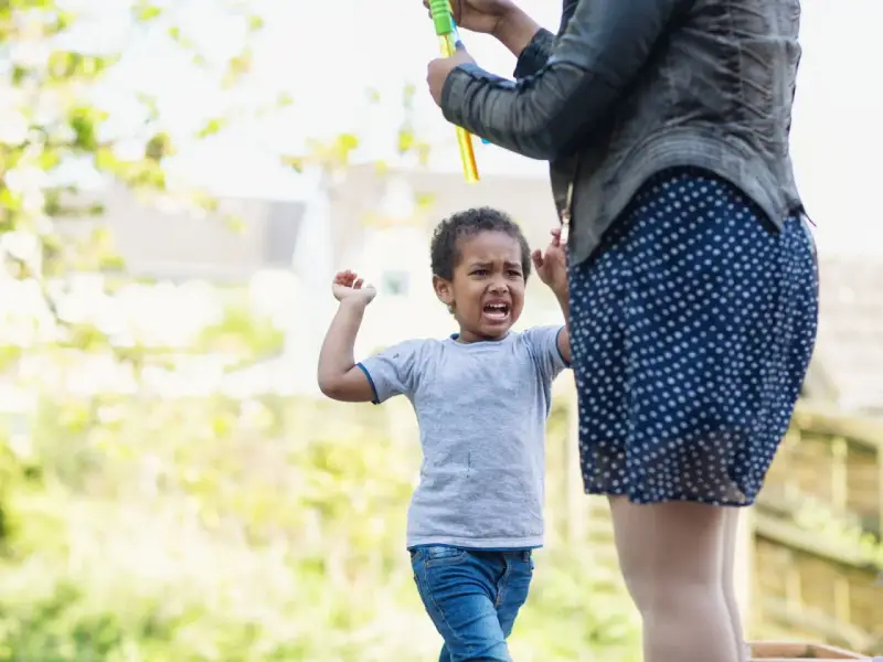 Kind weint, weil es nicht will, dass die Seifenblasen aufhören. Was tun, wenn Kinder schlagen? Geduld und Ablenkung helfen.